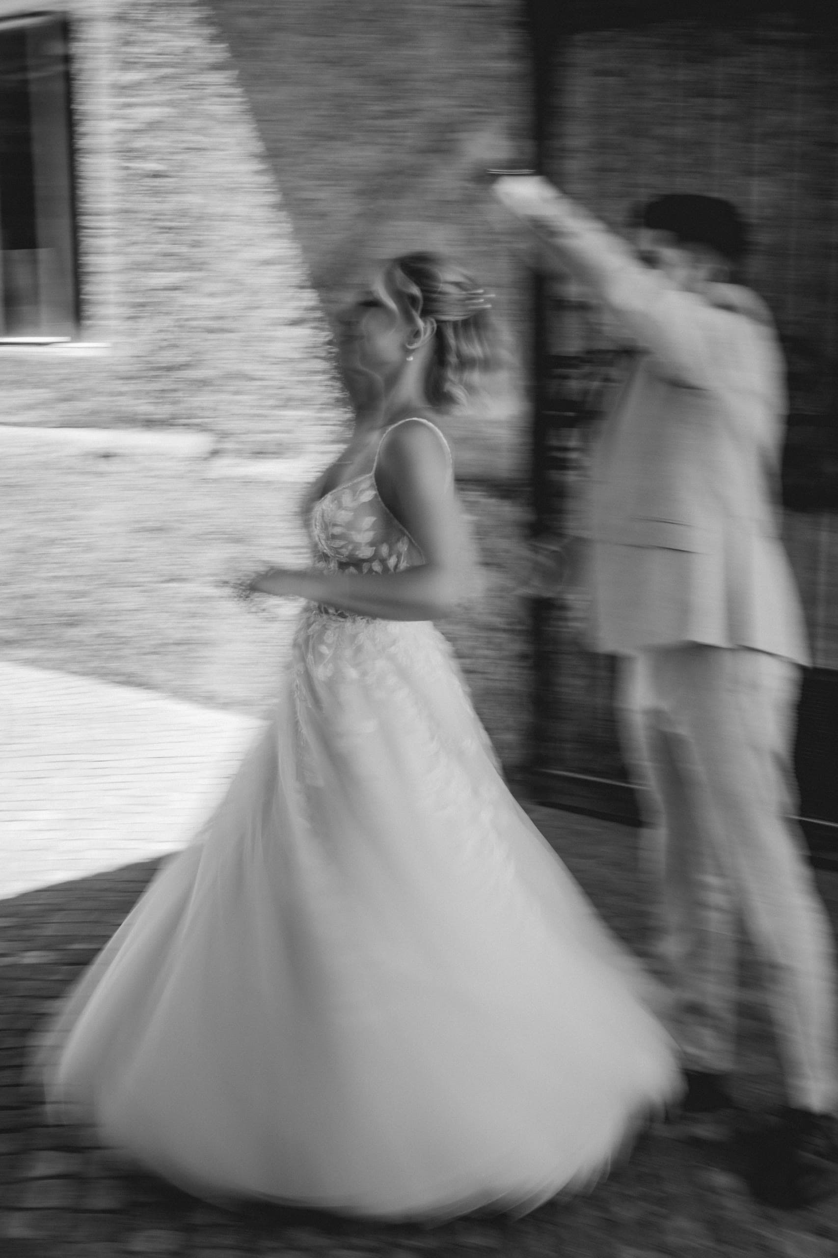 Motion blur of the bride's dress swirling as she dances outdoors, in black and white