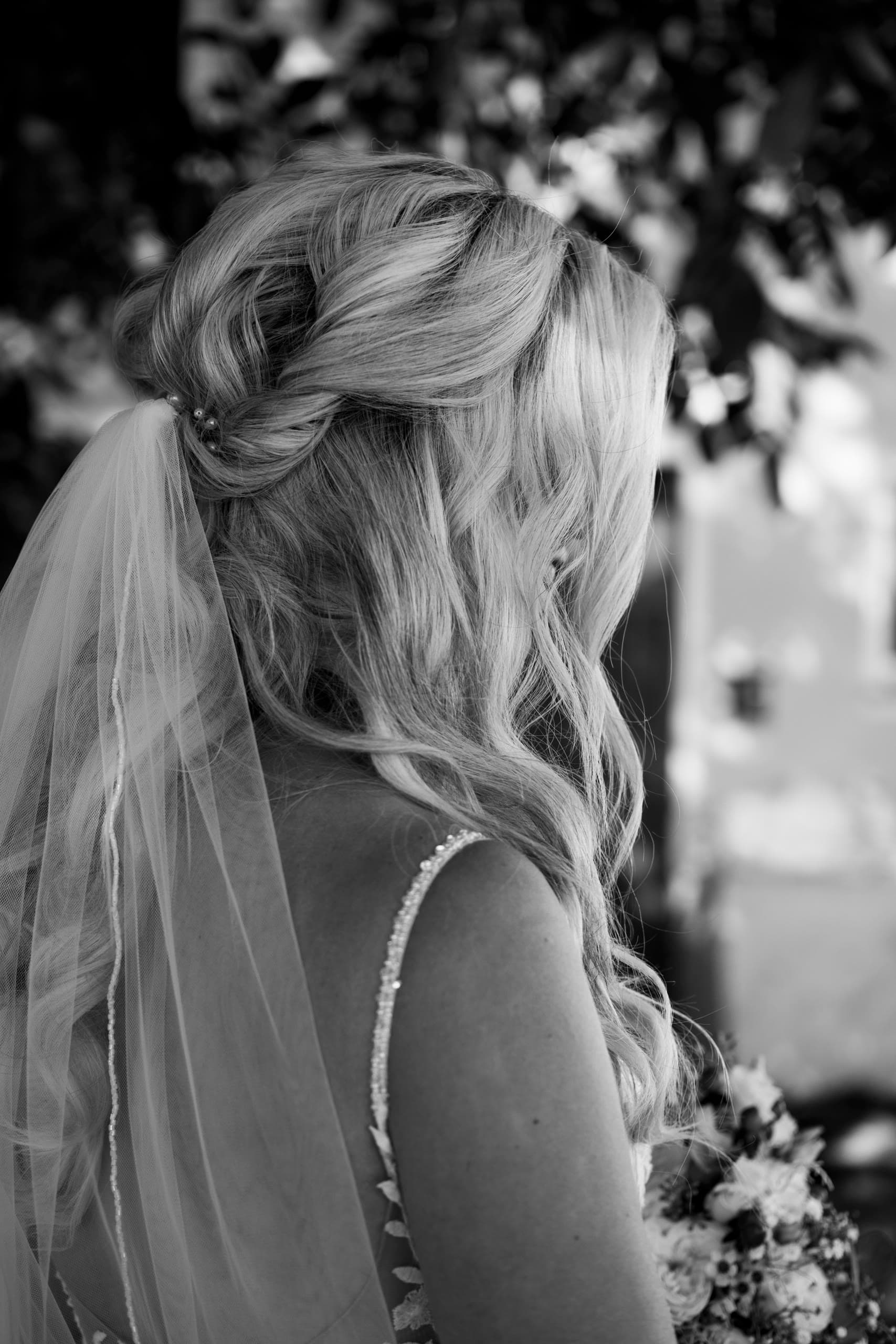 Bride's hair updo and veil seen from behind, in black and white
